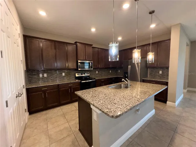 a kitchen with kitchen island granite countertop stainless steel appliances a sink stove and refrigerator