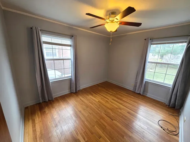 a view of empty room with wooden floor and fan