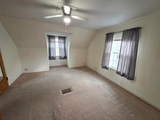 an empty room with windows and chandelier fan