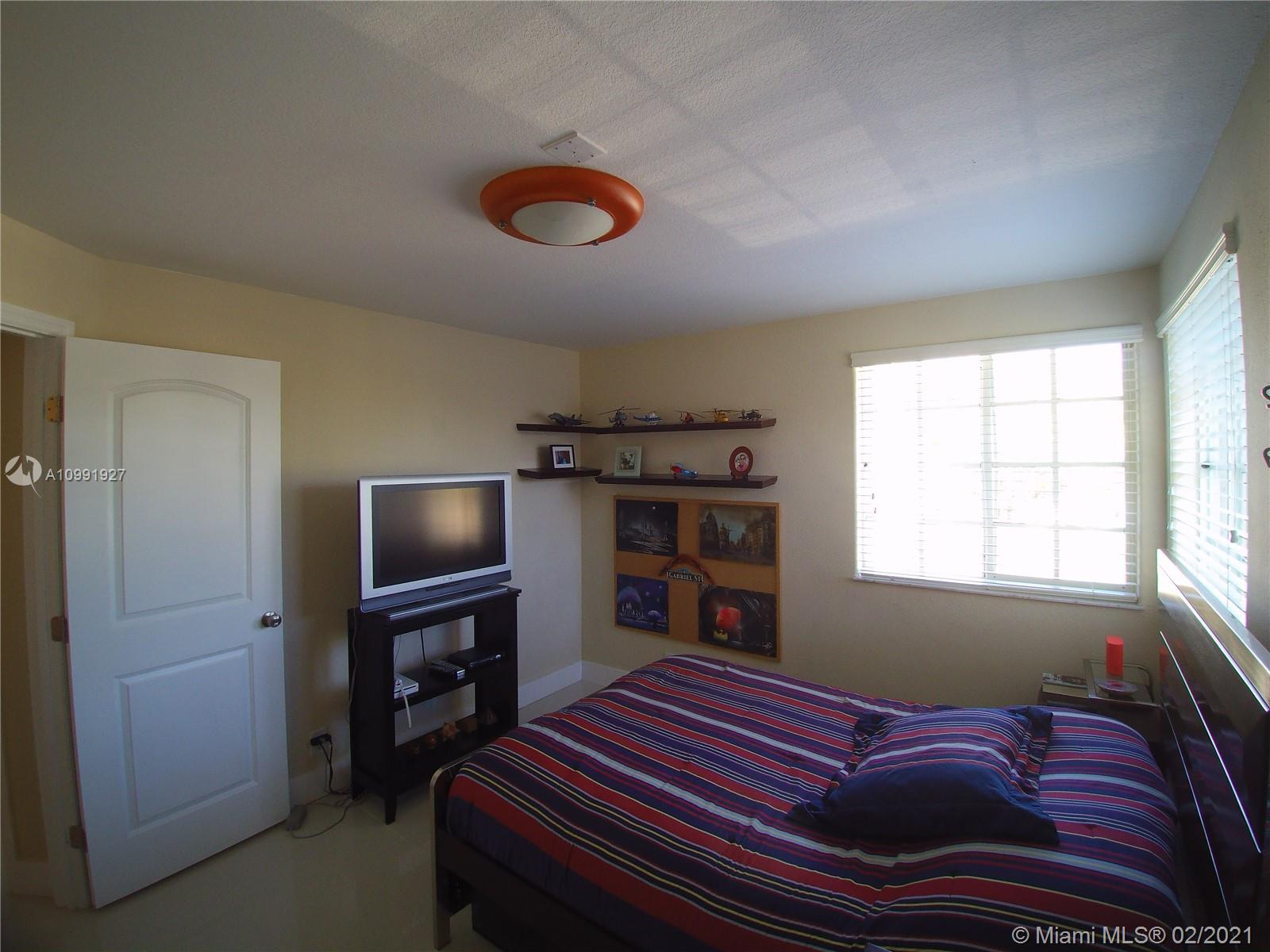 1055 San Luis Rey Weston, FL 33326 - Photo 27 of 36 a bedroom with a bed and a flat screen tv