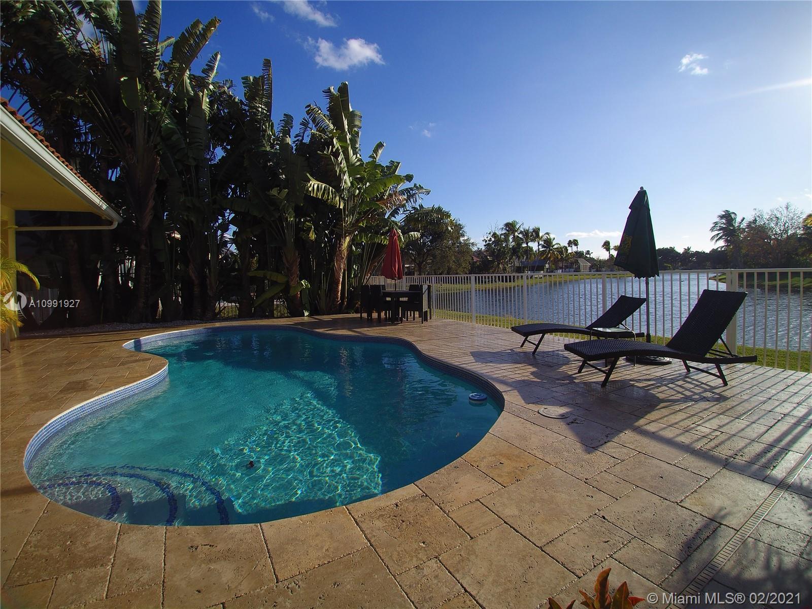 1055 San Luis Rey Weston, FL 33326 - Photo 33 of 36 a view of a swimming pool with lawn chairs under an umbrella