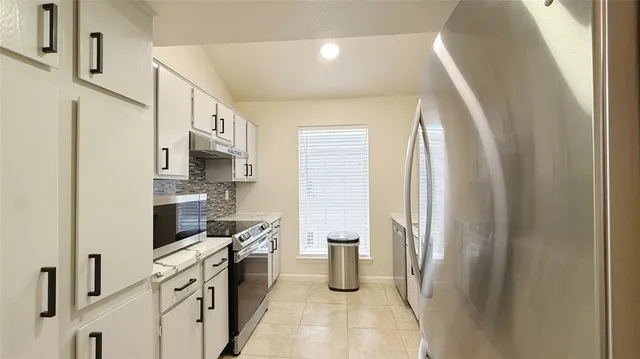 a kitchen with stainless steel appliances a refrigerator sink and white cabinets