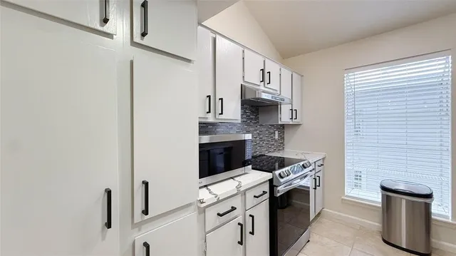 a kitchen with stainless steel appliances granite countertop white cabinets a stove top oven a sink and dishwasher