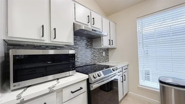 a kitchen with stainless steel appliances granite countertop white cabinets and stove