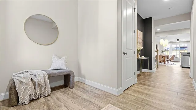 a view of a hallway to a livingroom with wooden floor and staircase