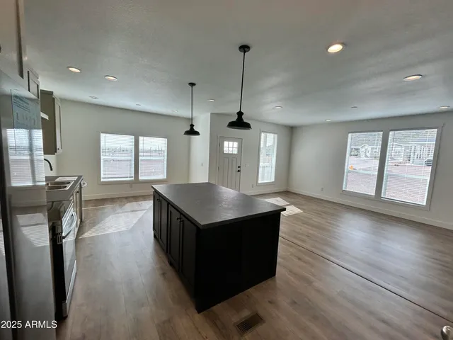 a kitchen with stainless steel appliances granite countertop a refrigerator a sink dishwasher a stove and white countertops with wooden floor