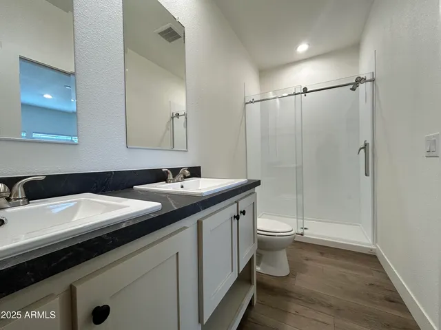a bathroom with a double vanity sink toilet and a mirror