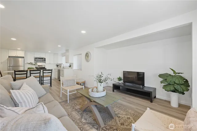 a living room with furniture kitchen view and a potted plant