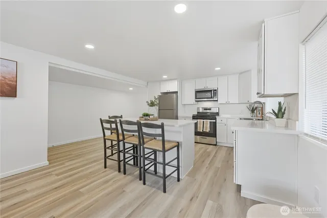 a kitchen with stainless steel appliances a dining table chairs and wooden floor
