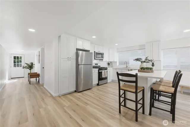 a kitchen with stainless steel appliances a dining table chairs and wooden floor
