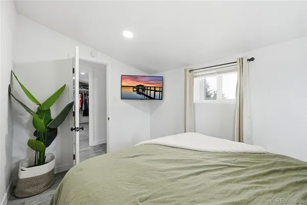 a bedroom with a large bed a potted plant and a window