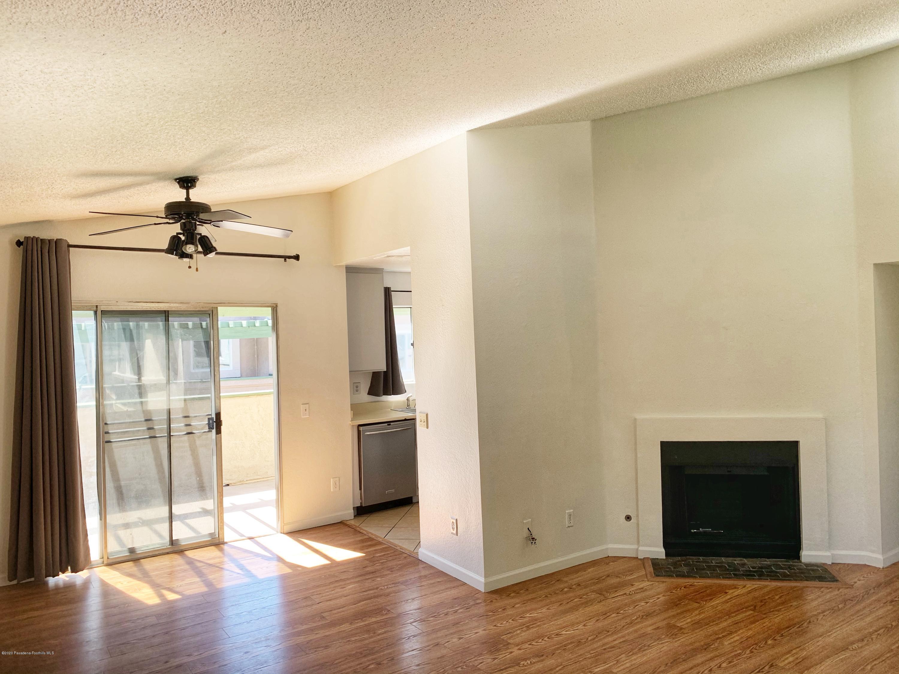an empty room with wooden floor fireplace and windows