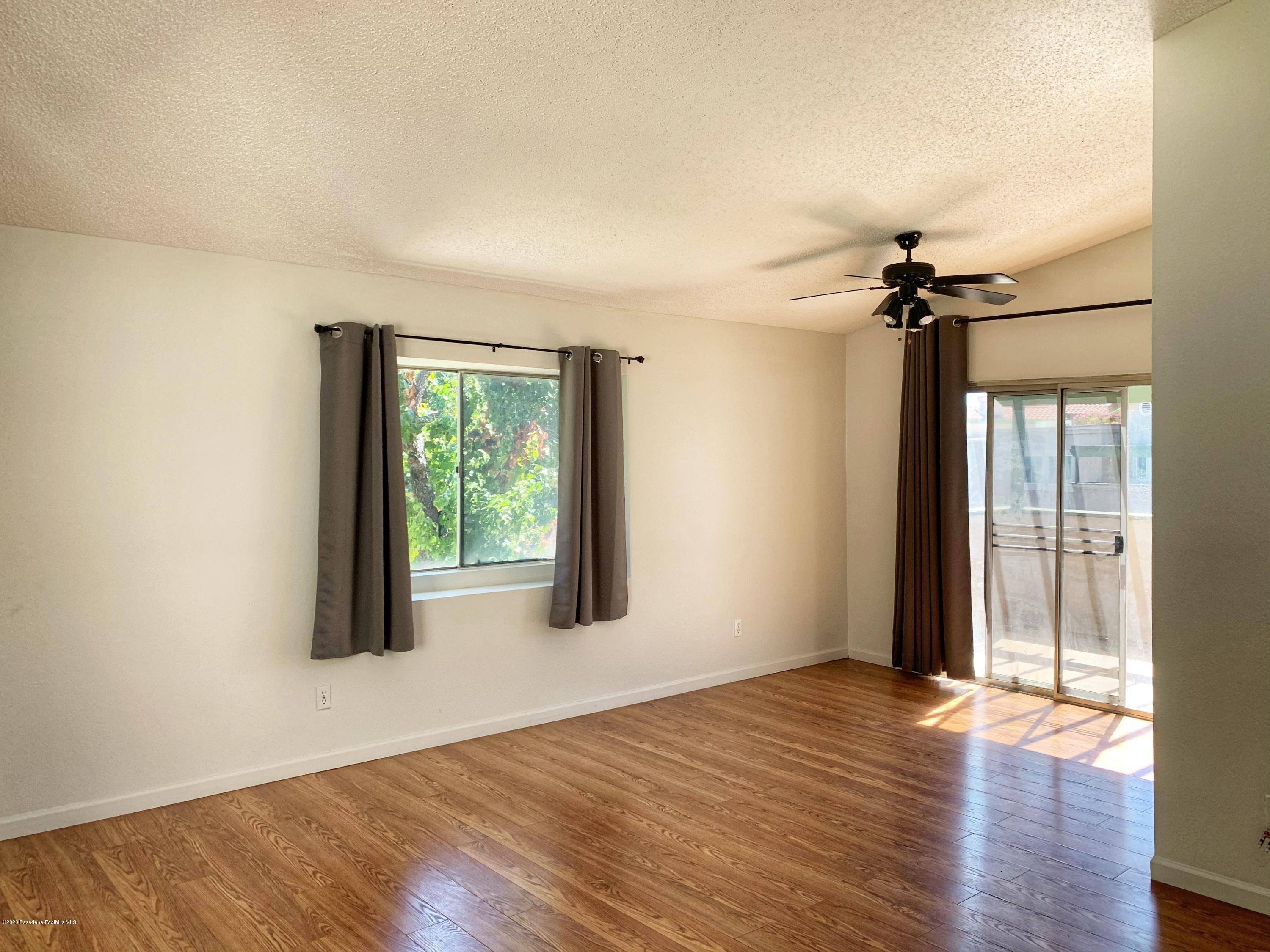 10245 Chaparral Way, Unit E Rancho Cucamonga, CA 91730 - Photo 5 of 31 an empty room with wooden floor fan and windows