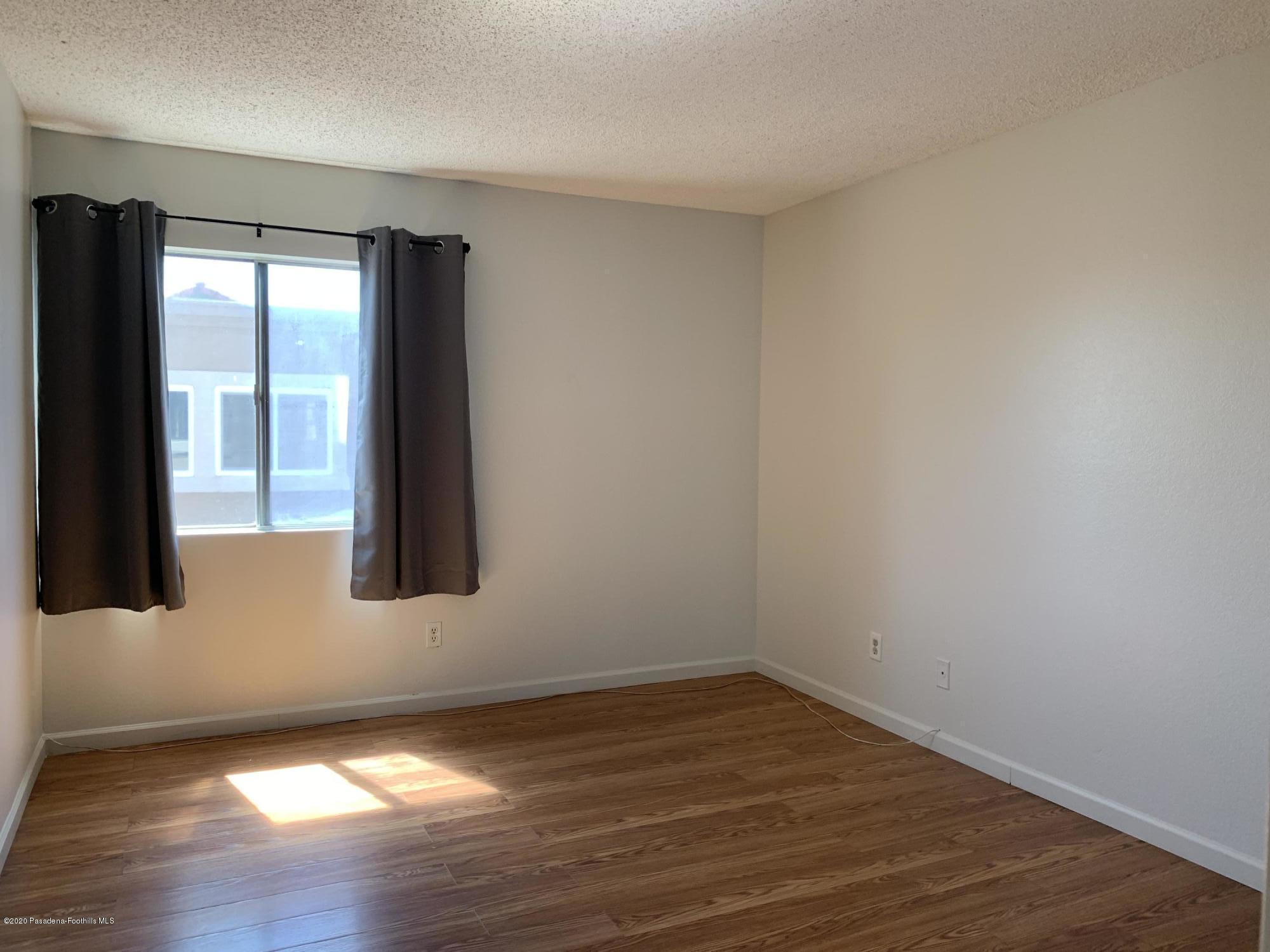 10245 Chaparral Way, Unit E Rancho Cucamonga, CA 91730 - Photo 8 of 31 a view of an empty room with wooden floor and a window