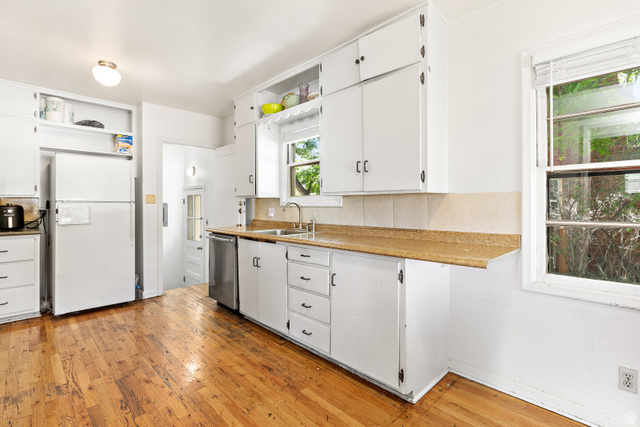 372 800 East Provo, UT 84606 - Photo 6 of 29 Kitchen featuring wood-finish flooring, white cabinetry, a stainless steel dishwasher, and a double-basin sink