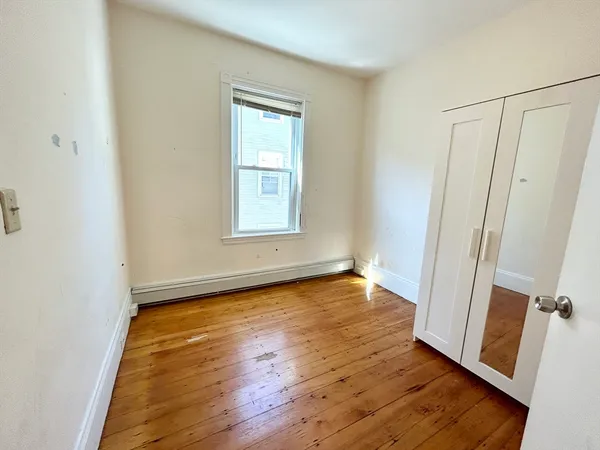 an empty room with wooden floor and window