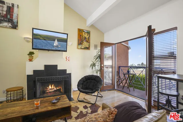 a living room with furniture kitchen view and a wooden floor