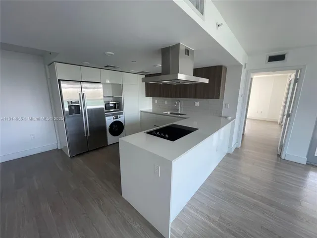 a kitchen with stainless steel appliances a stove a refrigerator a sink and wooden floors