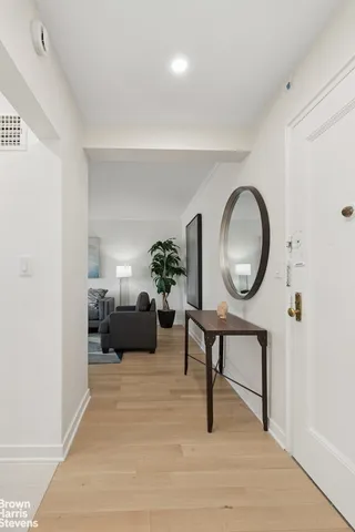 a living room with furniture a mirror and a potted plant