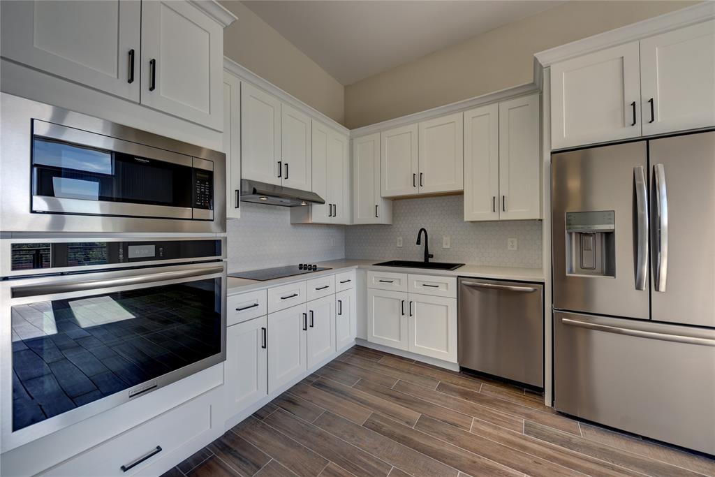 a kitchen with stainless steel appliances white cabinets a stove a microwave and a refrigerator