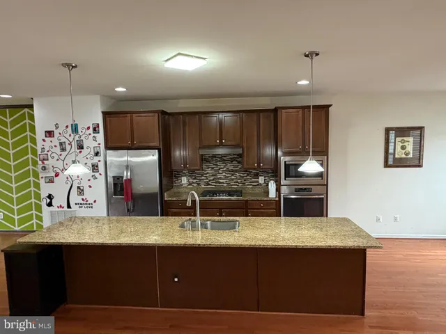 a kitchen with kitchen island granite countertop a sink and a refrigerator
