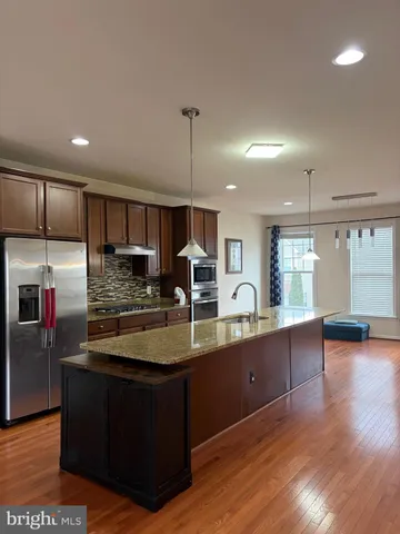 a kitchen with kitchen island a counter top space a sink stainless steel appliances and cabinets