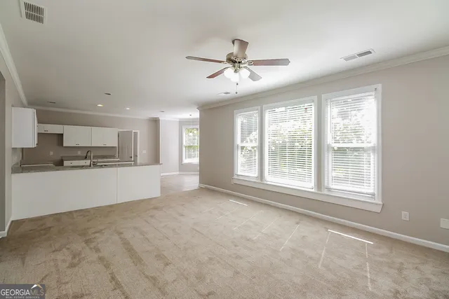 a view of an empty room with kitchen view and a window