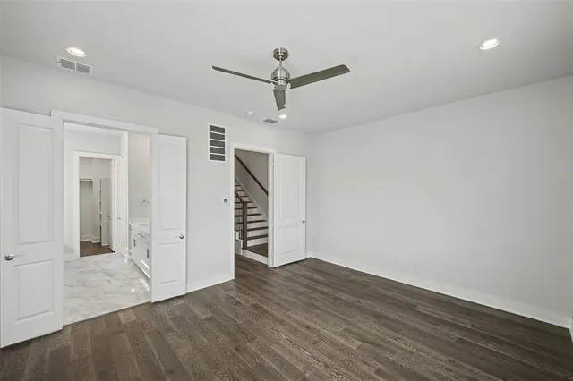 an empty room with wooden floor and ceiling fan