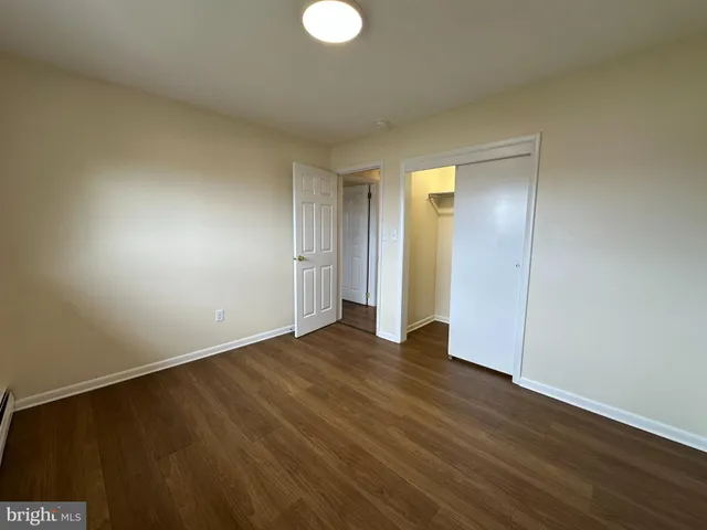 a view of an empty room with wooden floor and closet