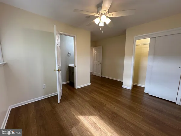 an empty room with wooden floor and ceiling fan