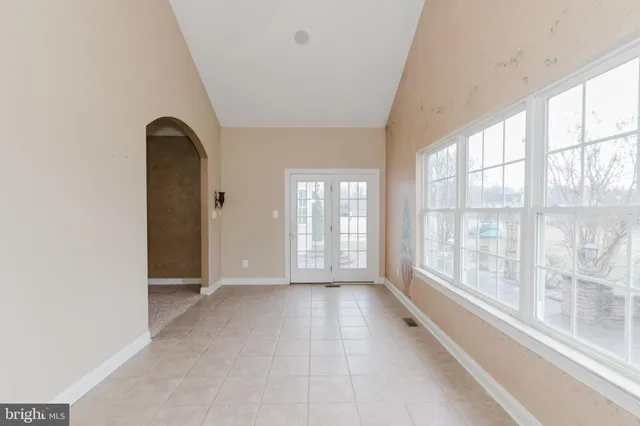 a view of an empty room with wooden floor and a kitchen
