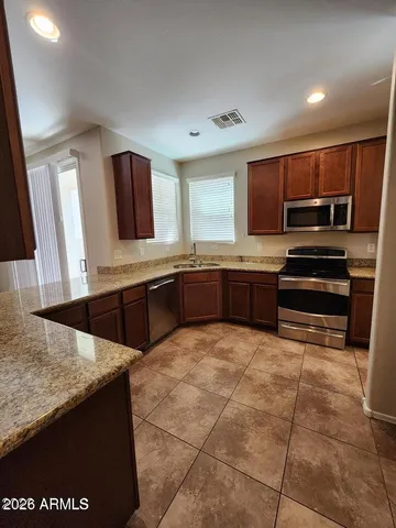 a large kitchen with granite countertop a stove a sink and a refrigerator