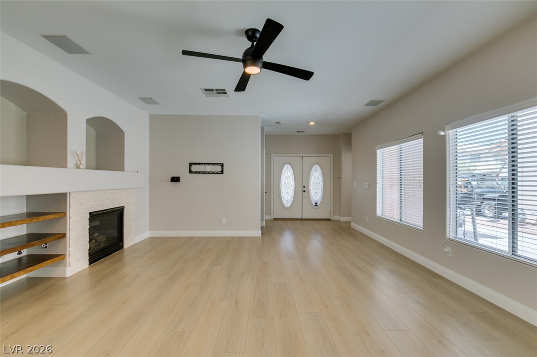 8909 Houston Ridge Avenue Las Vegas, NV 89178 - Photo 8 of 45 A spacious living area featuring light wood flooring, a modern ceiling fan, and an inviting fireplace with built-in shelving.