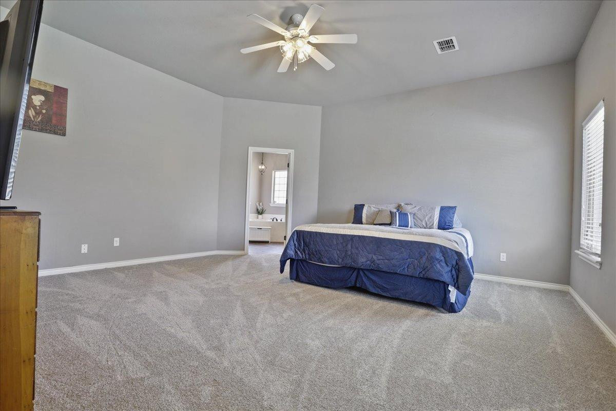 6304 County Road 7475 Lubbock, TX 79424 - Photo 16 of 28 a spacious bedroom with a bed and a chandelier