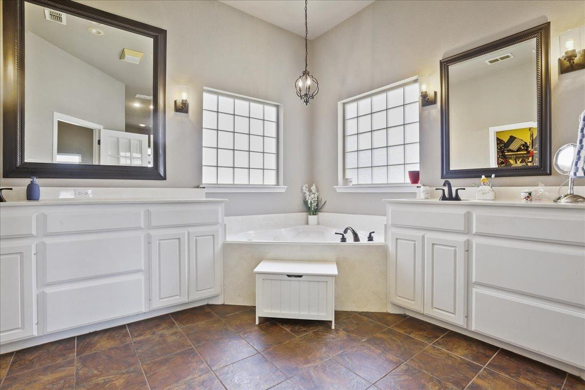 6304 County Road 7475 Lubbock, TX 79424 - Photo 18 of 28 a bathroom with a sink vanity tub and a mirror