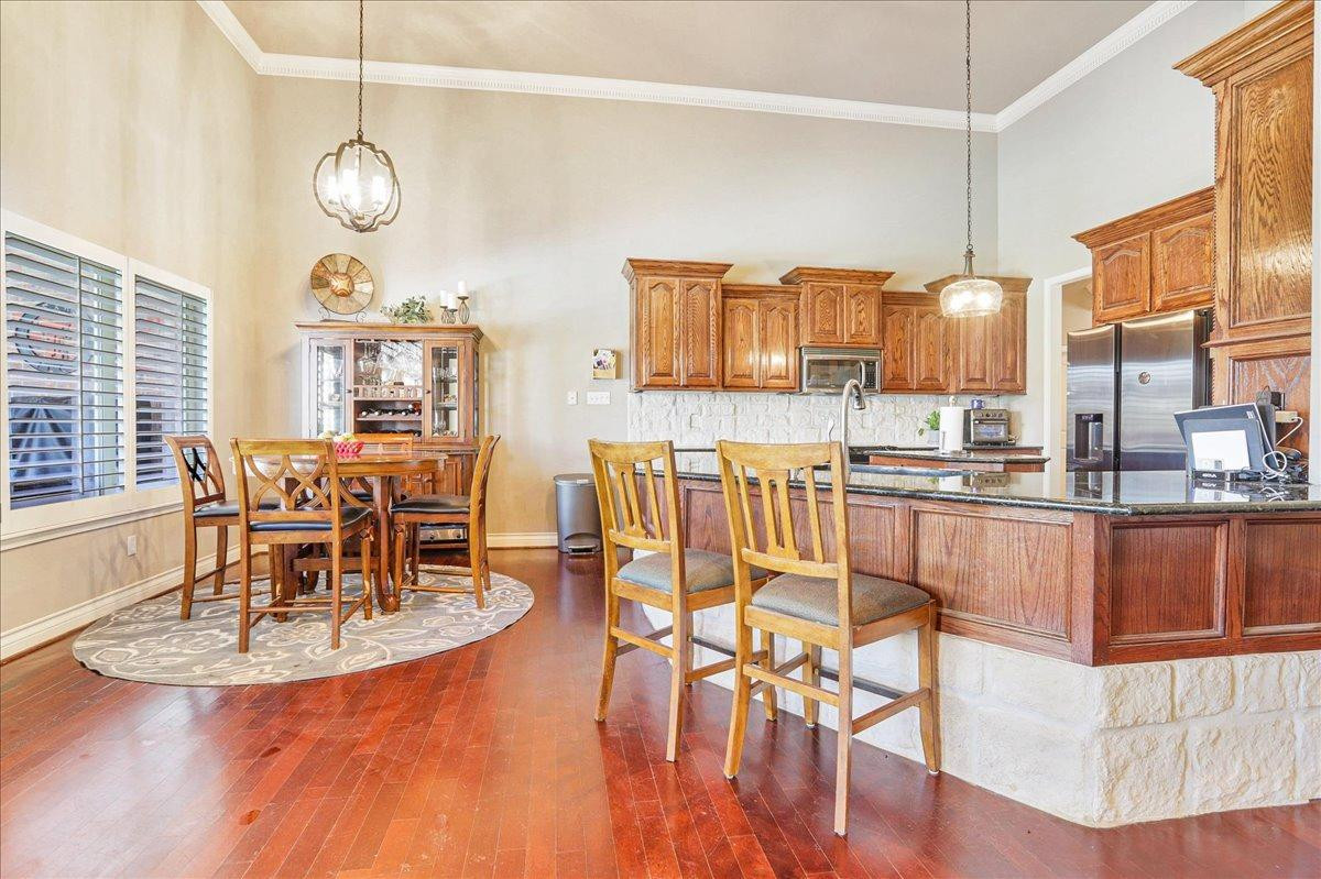 6304 County Road 7475 Lubbock, TX 79424 - Photo 8 of 28 a dining room with wooden floor a chandelier a glass table and chairs