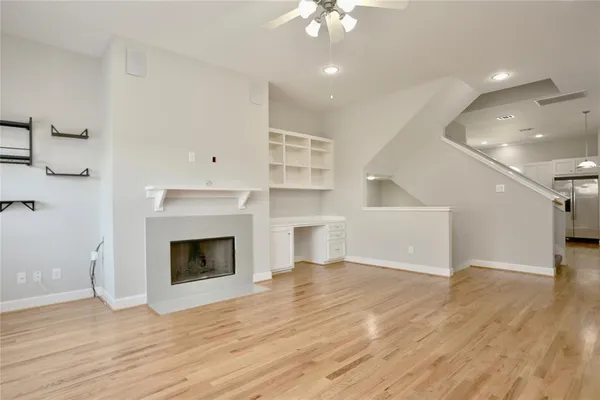 an empty room with wooden floor fireplace and windows