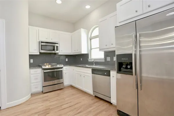 a kitchen with stainless steel appliances granite countertop a stove a sink and a refrigerator
