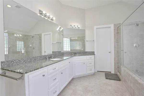 a bathroom with a granite countertop double vanity sink and mirror