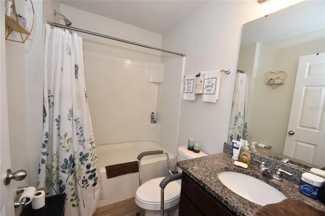 a bathroom with a granite countertop sink toilet a mirror a vanity and shower