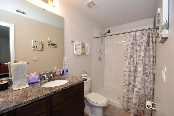 a bathroom with a granite countertop sink toilet and shower