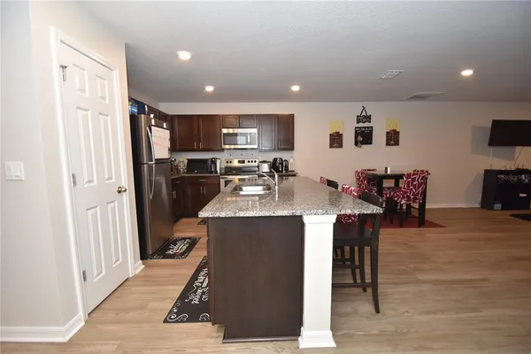 a kitchen with stainless steel appliances kitchen island granite countertop a refrigerator and a dining table