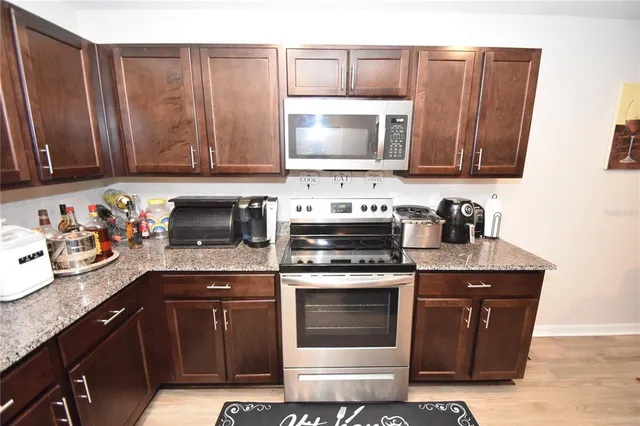 a kitchen with granite countertop wooden cabinets and a stove top oven