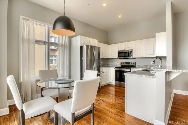 a kitchen with stainless steel appliances a dining table chairs microwave and sink