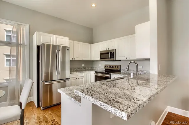 a kitchen with stainless steel appliances granite countertop a refrigerator microwave and sink