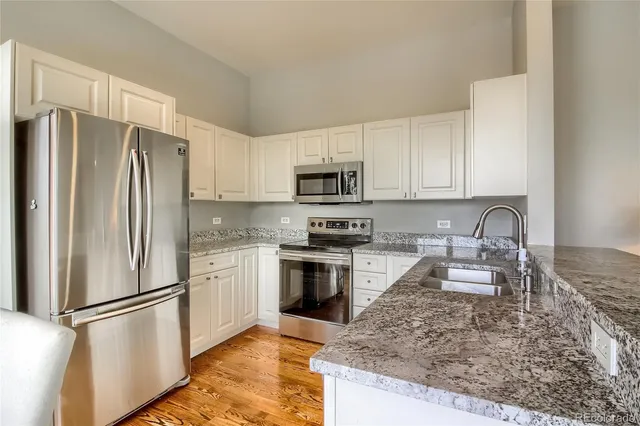a kitchen with granite countertop a refrigerator stove and sink