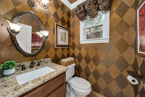 a bathroom with a granite countertop toilet a sink and a mirror