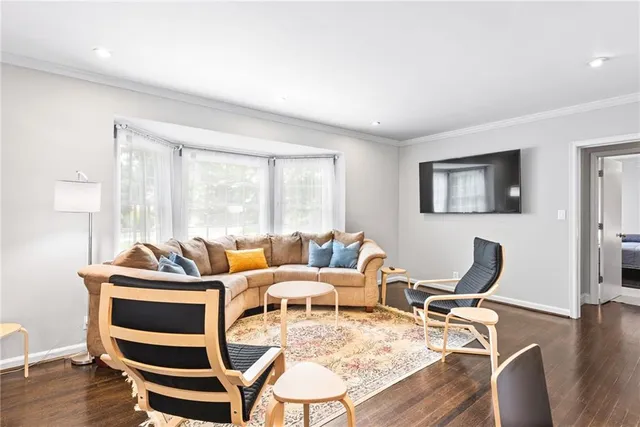 a living room with furniture a wooden floor and next to a window