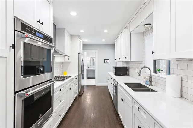 a kitchen with white cabinets and appliances