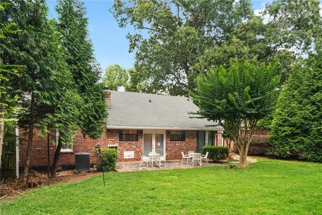 a front view of a house with garden and trees